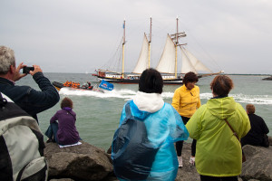Hanse Sail Rostock Warnemünde Touristen auf der Mole beobachten ein Segelschiff und Schlauchboot auf der Ostsee