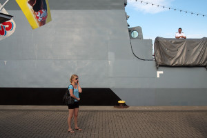 Hanse Sail Rostock Warnemünde Frau mit Handy und die Korvette Braunschweig der Deutschen Marine mit Soldat