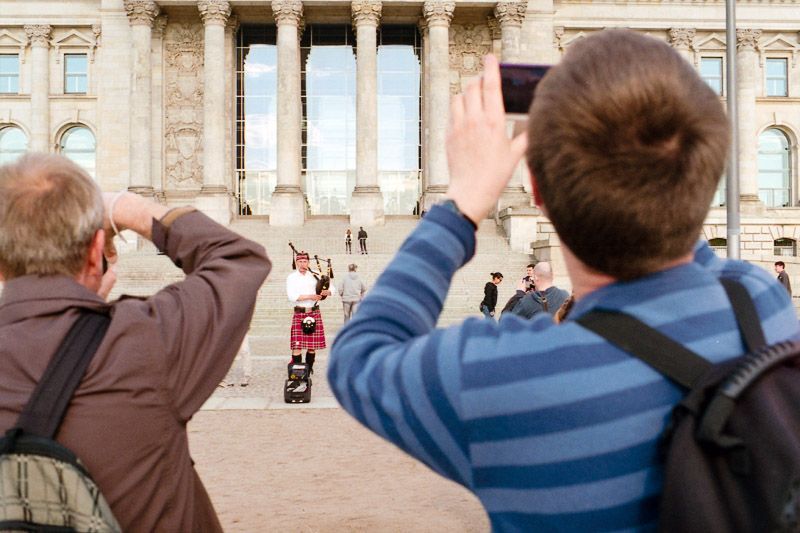 Berlin Besucher fotografieren Fotos vom Straßenmusiker und Dudelsackspieler vor dem Reichstag